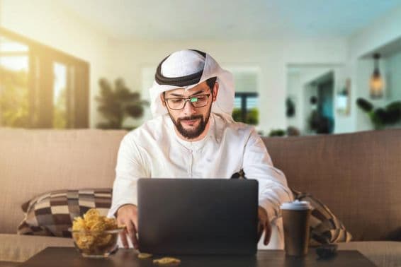 Homem árabe estudando com um laptop.