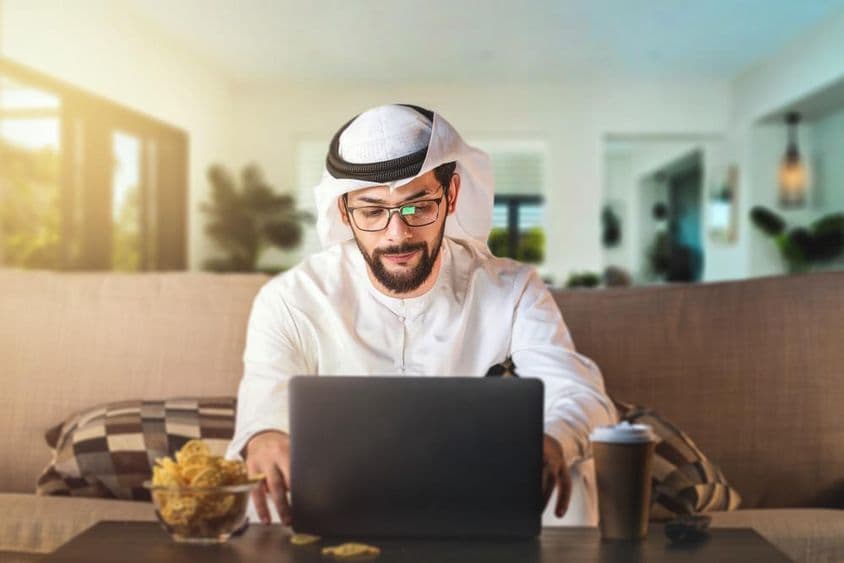 Homem árabe estudando com um laptop.