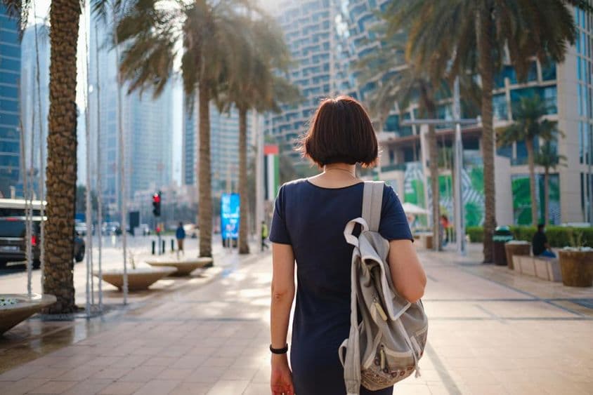 Mulher caminhando em Dubai com uma mochila.