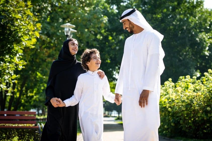 Família muçulmana caminhando em um parque de Dubai.