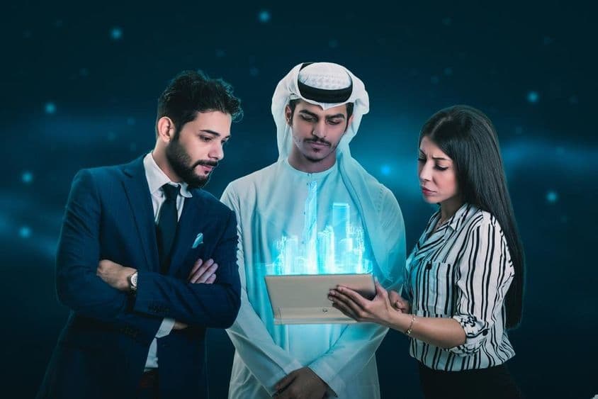 Dois homens e uma mulher examinando um holograma.