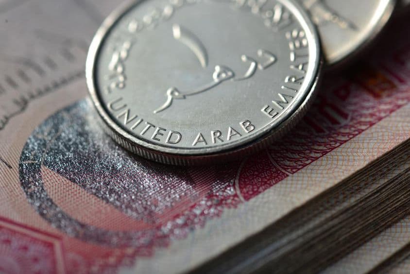 Moeda de um dirham sobre uma pilha de notas.