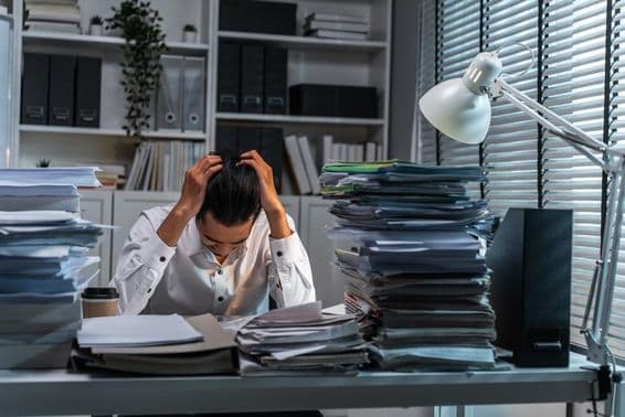 Trabalhador de escritório segurando a cabeça devido a sobrecarga de trabalho.