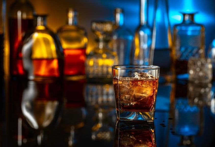 Whisky com gelo em uma mesa preta em um bar.