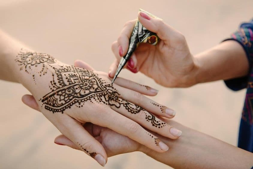 Henna sendo aplicada na mão de uma mulher.