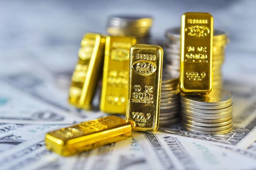 Ouro de investimento 999,9 de pureza, sobre papel e moedas de dólar.