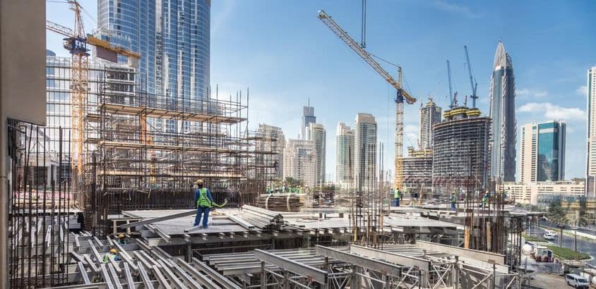 Construção em Dubai, um trabalhador empilhando tábuas de madeira.