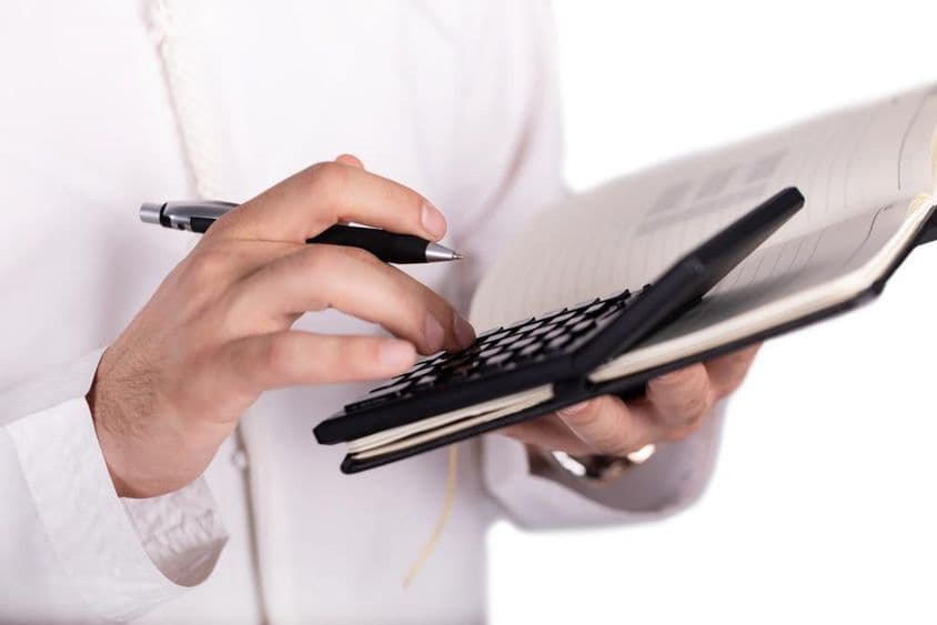 Homem de negócios árabe segurando uma calculadora.