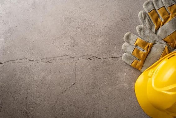 Hora do intervalo, capacete amarelo e luvas de trabalho colocados em uma superfície de concreto rachada.