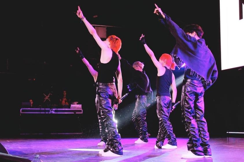 Banda de K-Pop dançando no palco.
