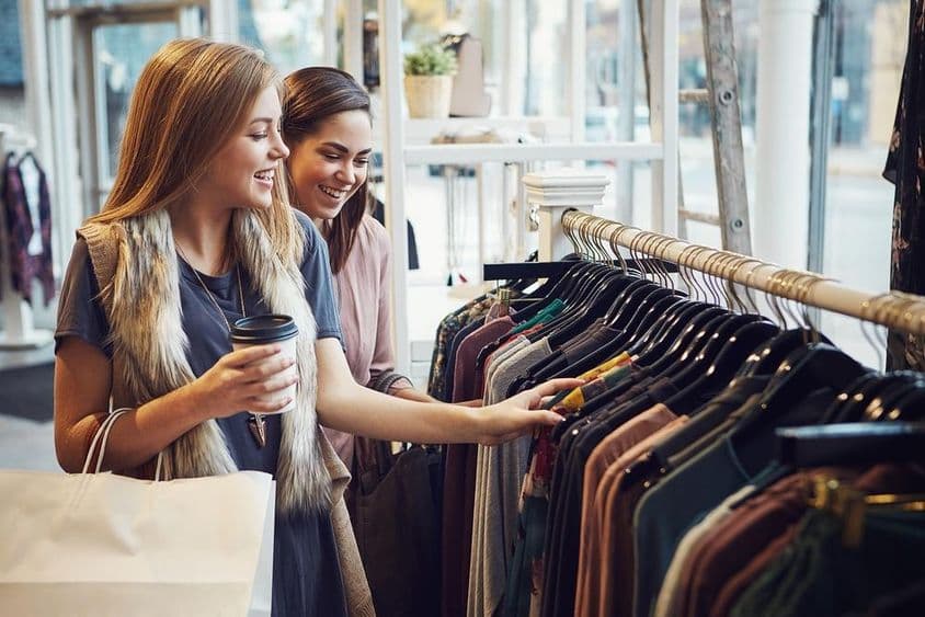 Mulheres rindo e tomando café em uma boutique.