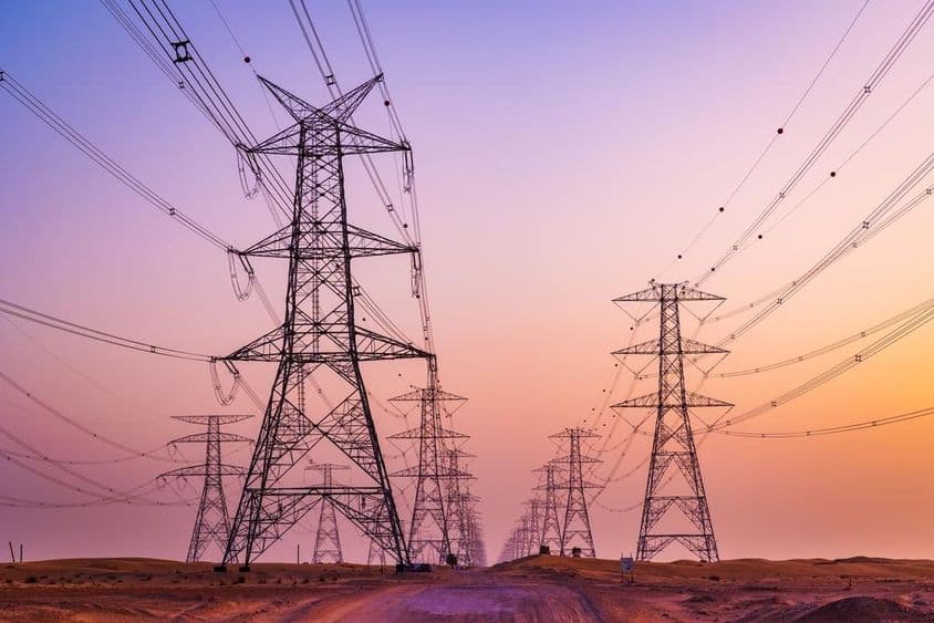 Torre de alta tensão com linhas de transmissão de energia contra céu colorido no deserto de Al Qudra, Dubai, Emirados Árabes Unidos.