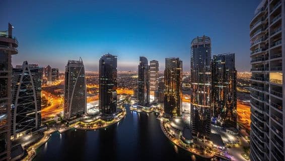 Panorama de edifícios residenciais na área JLT, torres e arranha-céus iluminados.