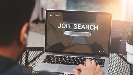 Homem usando laptop para busca de emprego.