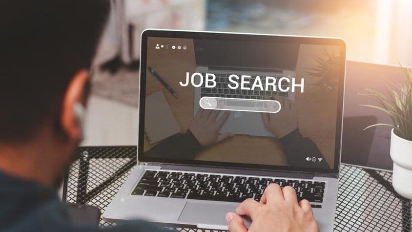 Homem usando laptop para busca de emprego.