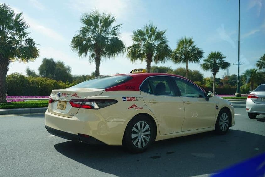 Táxi de Dubai com teto vermelho dirigindo na estrada.