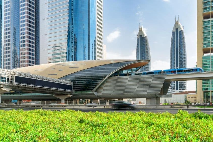 Um metrô de Dubai chega à estação Centro Financeiro no centro de Dubai, nos Emirados Árabes Unidos, com arranha-céus deslumbrantes ao fundo.