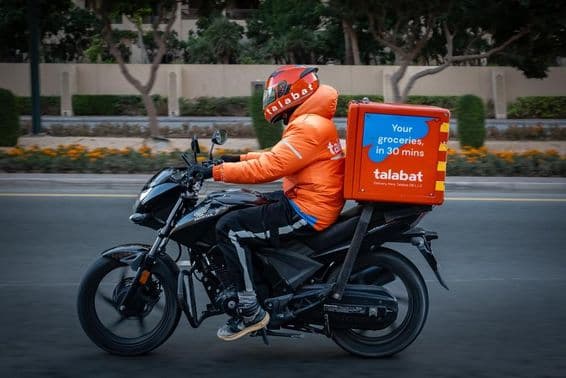 Motociclista entregando comida, navegando por ruas movimentadas em Dubai.
