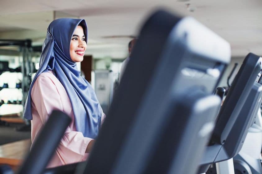 Mulher muçulmana se exercita em uma academia, usando um hijab.
