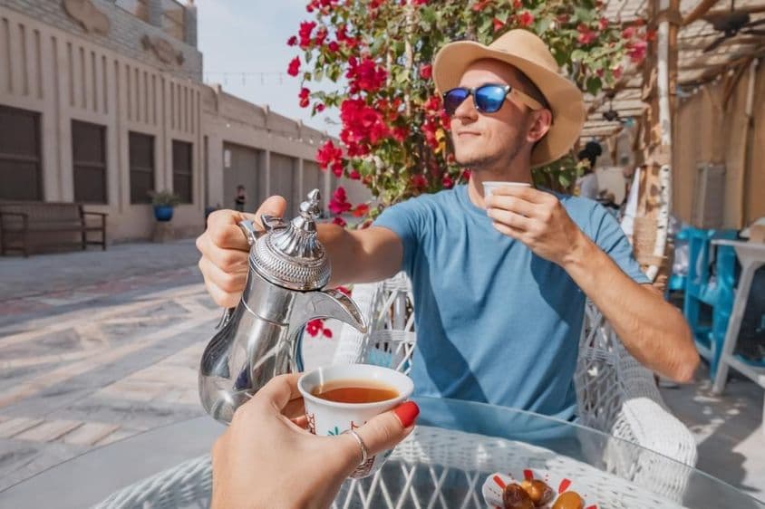 Um homem em Dubai descansando em um café árabe, servindo café aromático de uma cafeteira dallah.