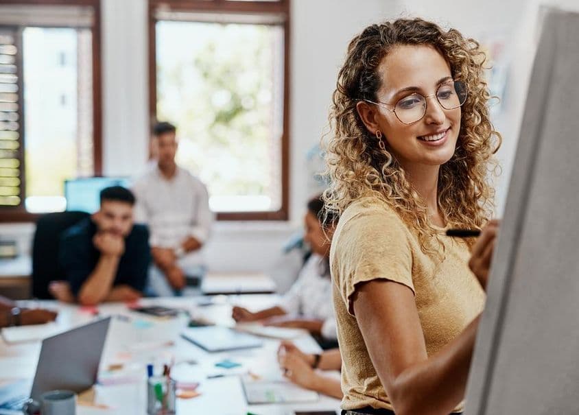 Reunião de coaching e apresentação com uma designer em um local de trabalho criativo para desenvolvimento de habilidades.