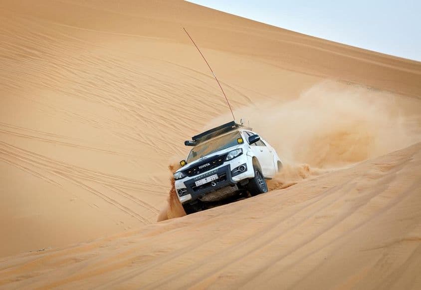 Veículo 4x4 correndo em uma duna.