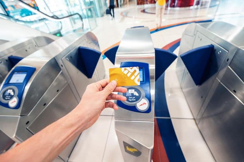 Um passageiro masculino usa um cartão NOL dourado no metrô de Dubai para passar por uma catraca e viajar no primeiro vagão.