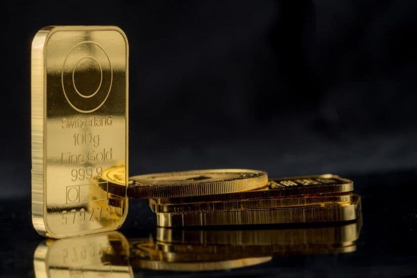 Barras de ouro de vários pesos sobre um fundo espelhado preto.