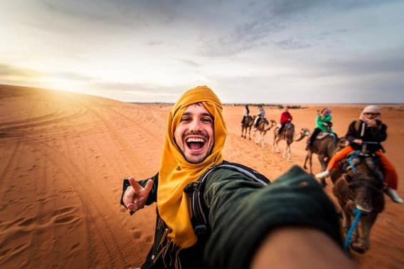 Turista feliz desfrutando de passeio de camelo no deserto.