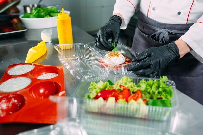 O chef prepara comida no restaurante e embala em recipientes descartáveis.