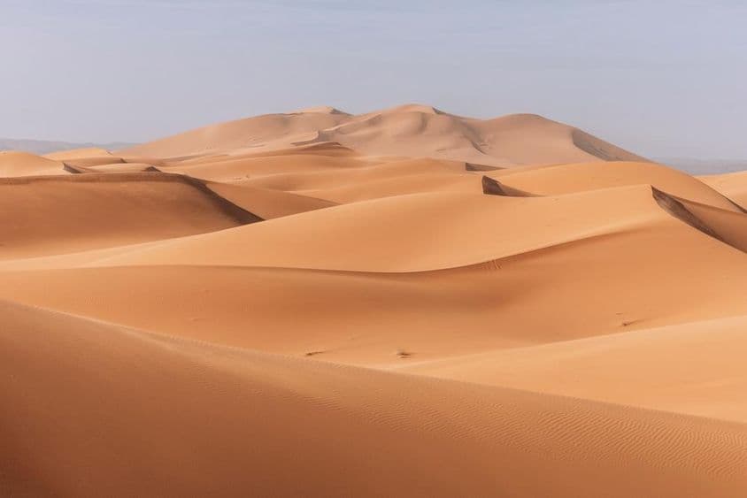 Dunas imponentes, pôr do sol dourado sobre uma paisagem calma e silenciosa.