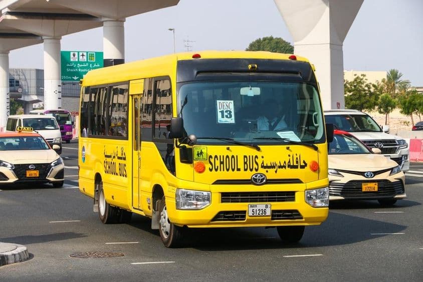 Ônibus escolar Toyota Coaster em uma rua da cidade.