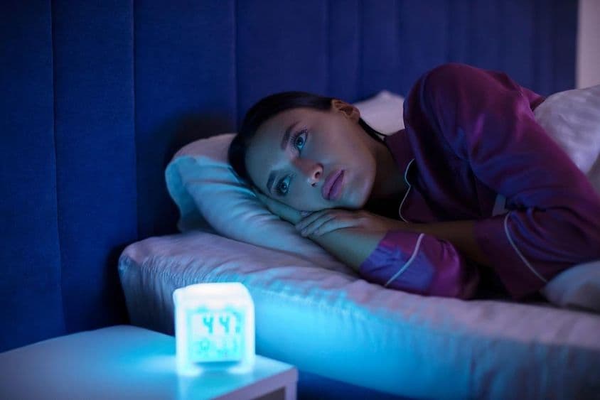 Mulher triste e insonada deitada na cama, olhando para longe, incapaz de dormir, sofrendo de insônia.