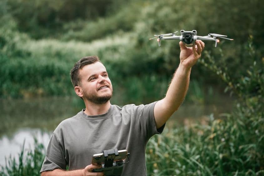 Instrutor de drones com drone na mão durante aula ao ar livre.