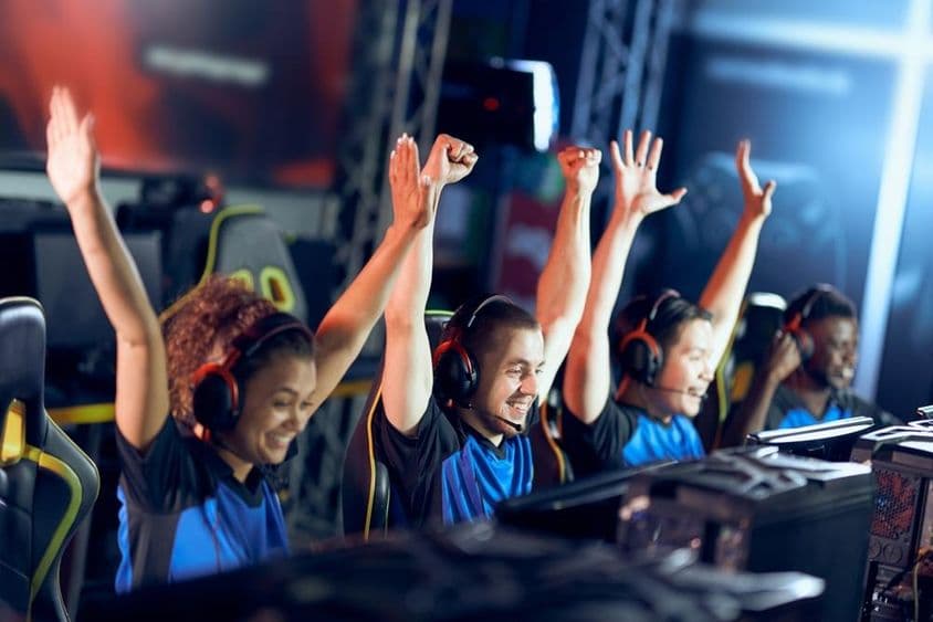 Uma equipe jubilante de gamers de esportes eletrônicos celebra o sucesso durante uma competição de esports.
