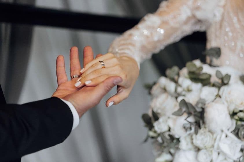 Noivos de mãos dadas, noiva vestindo um vestido branco.