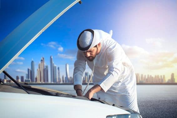 Um homem árabe inspecionando seu carro, capô aberto.
