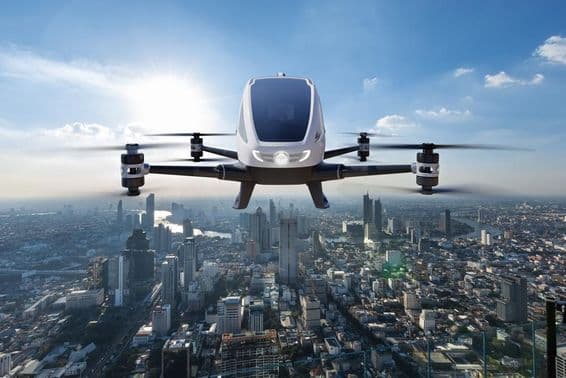 Veículo aéreo autônomo e sem motorista voando contra um fundo urbano.