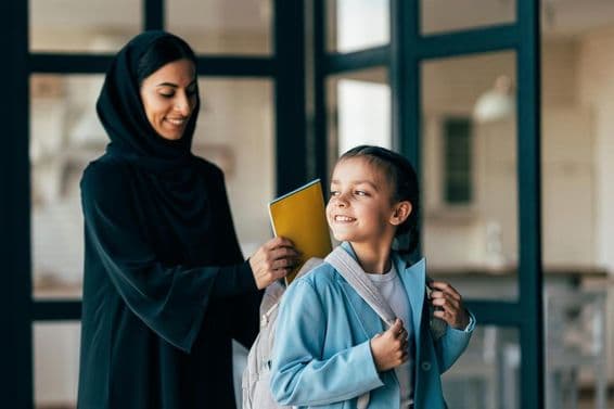 Família árabe tradicional de Dubai, menina jovem indo para a escola pela manhã.