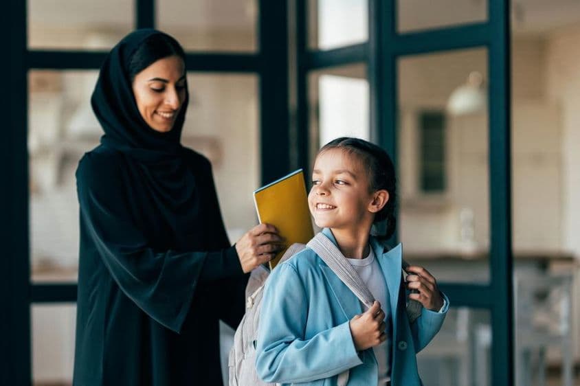 Família árabe tradicional de Dubai, menina jovem indo para a escola pela manhã.