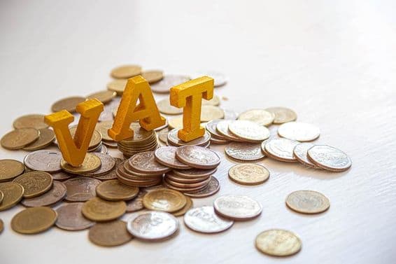 Moedas sobre uma mesa com as letras "Imposto" acima.