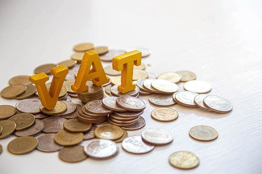Moedas sobre uma mesa com as letras "Imposto" acima.