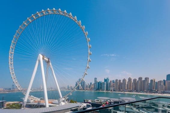 Roda-gigante Ain Dubai com arranha-céus e mar ao fundo.