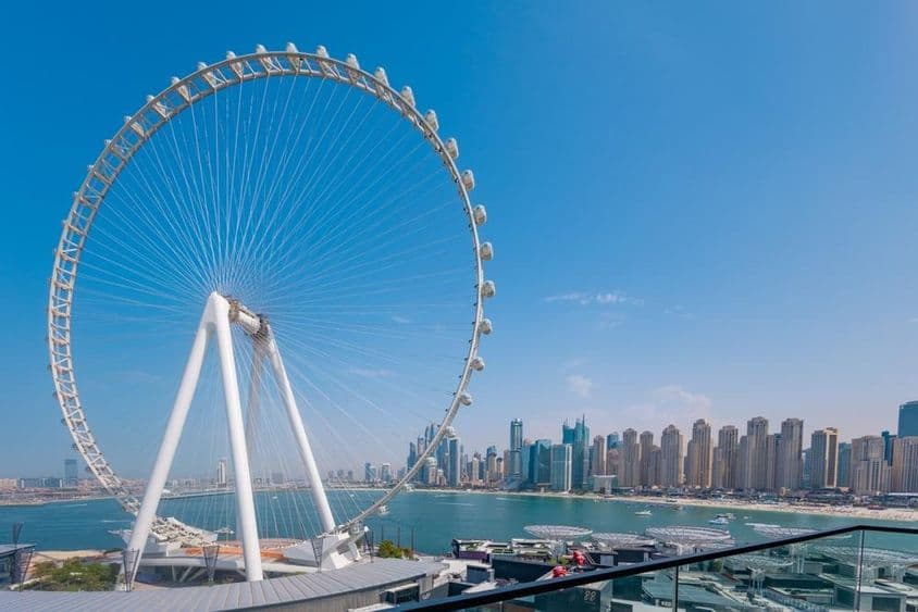 Roda-gigante Ain Dubai com arranha-céus e mar ao fundo.