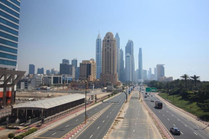 Vista de rua em Dubai com arranha-céus e bonde ao fundo.