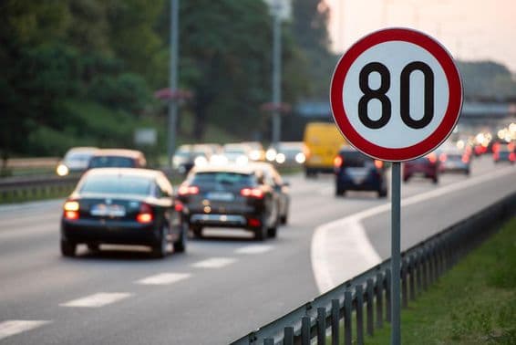 Sinal de limite de velocidade de 80 km/h em uma estrada movimentada.