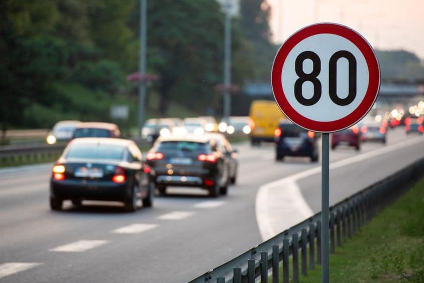 Sinal de limite de velocidade de 80 km/h em uma estrada movimentada.