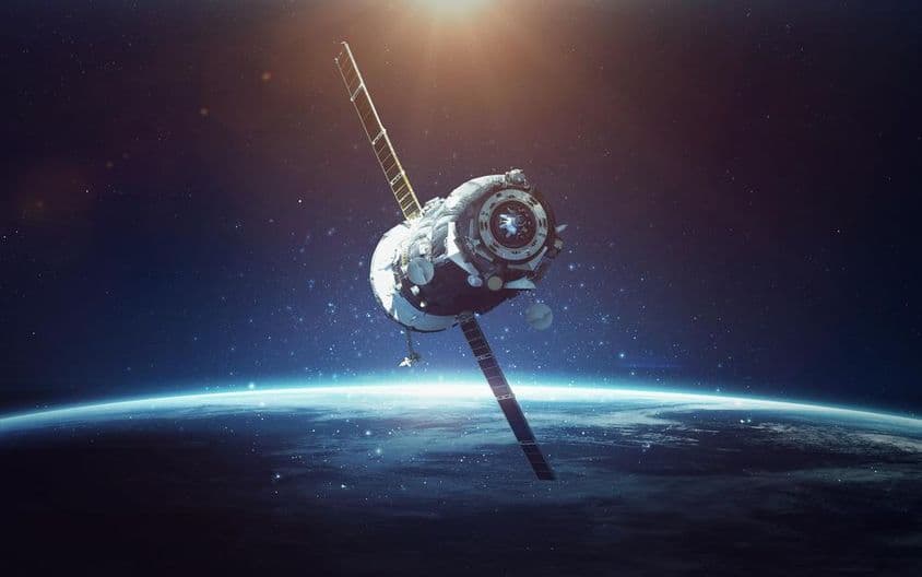 Satélite com planeta azul ao fundo.