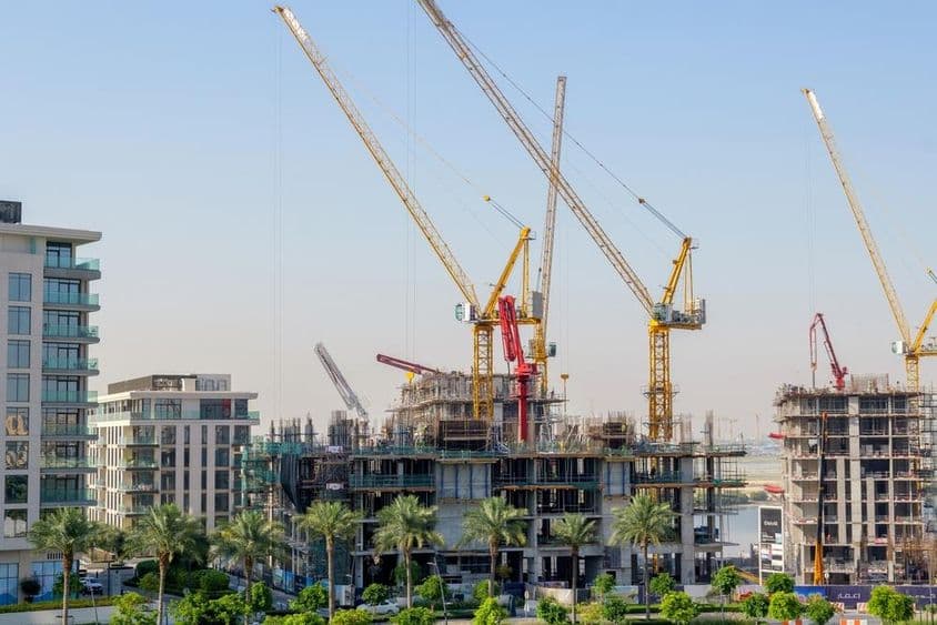 Edifícios residenciais em construção com guindastes no porto de Dubai Creek.