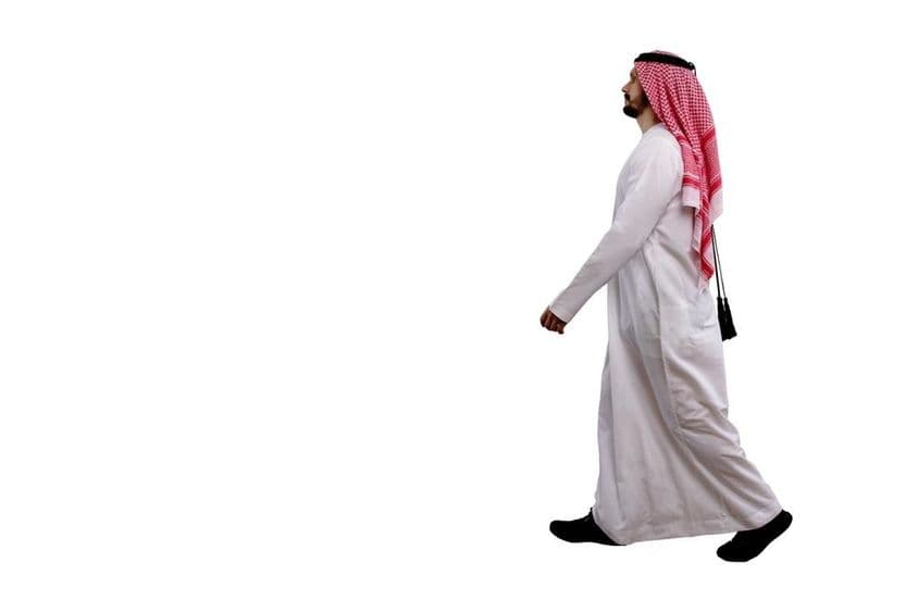 Homem árabe caminhando em traje tradicional.